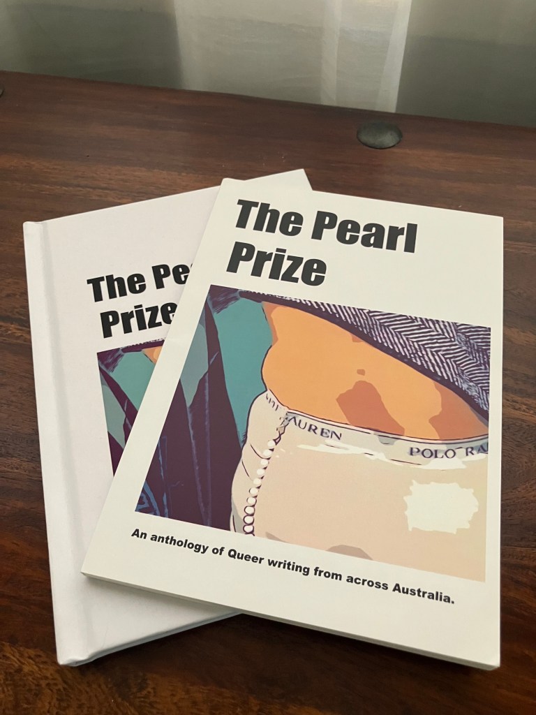Two copies of 'The Pearl Prize' anthology, featuring queer writing from across Australia, displayed on a wooden surface.
